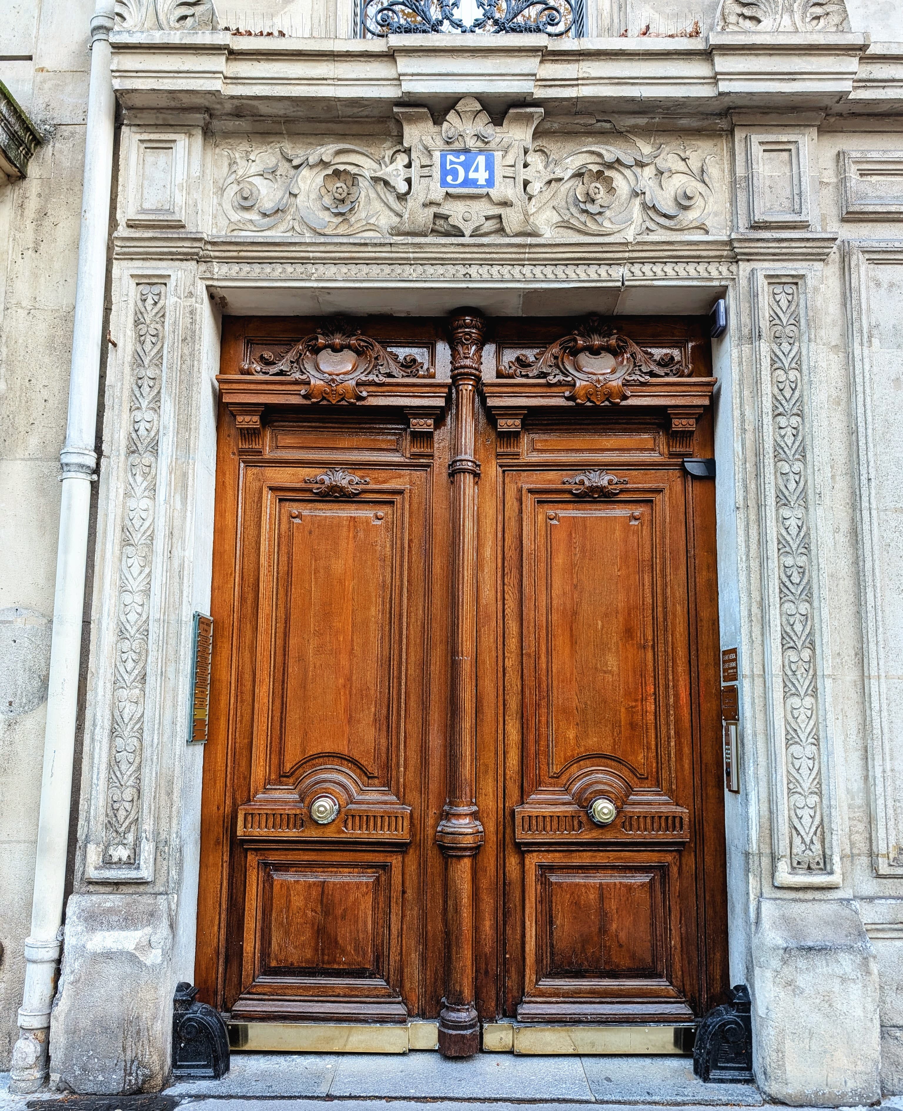 Portes doubles en bois sculpté ornées de détails complexes sous le numéro bleu 54.